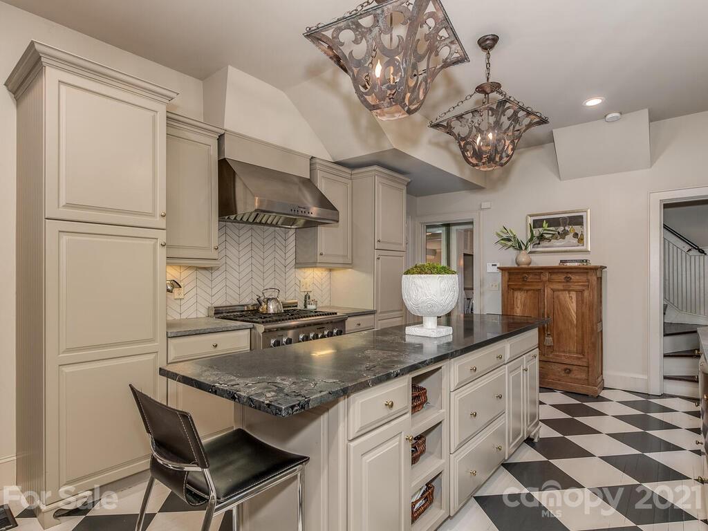 2001 Queens Road East Charlotte, NC 28207 - Photo 13 of 39 a kitchen with stainless steel appliances granite countertop a stove a refrigerator and a dining table with wooden floor