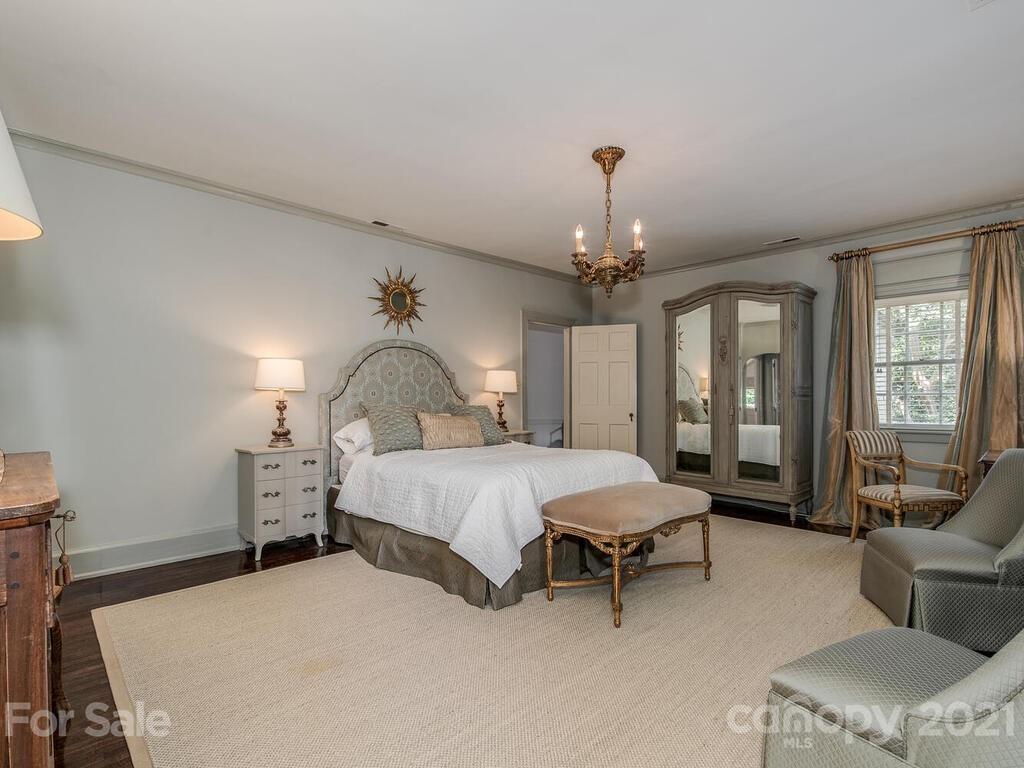 2001 Queens Road East Charlotte, NC 28207 - Photo 18 of 39 a spacious bedroom with a bed large window and a chandelier