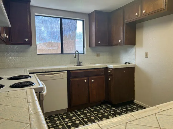 a kitchen with a sink a stove cabinets and a window