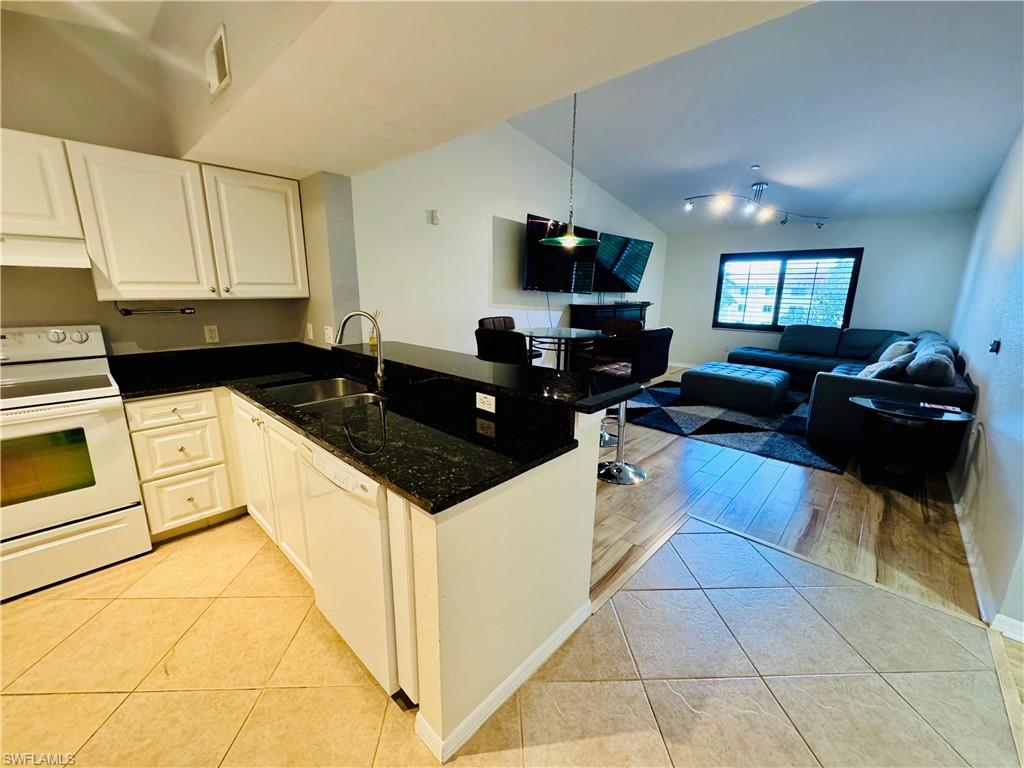 8244 Key Royal Circle, Unit 633 Naples, FL 34119 - Photo 4 of 28 a kitchen with granite countertop a sink a stove and a microwave