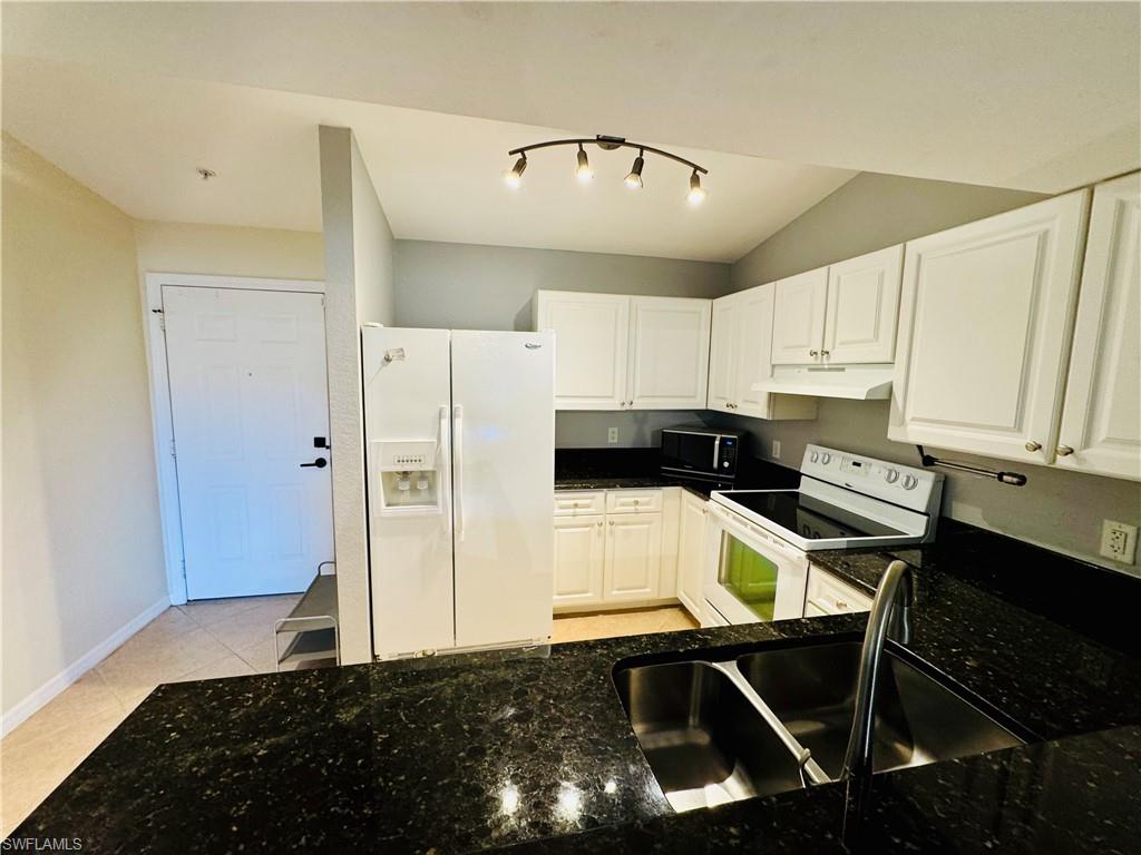 8244 Key Royal Circle, Unit 633 Naples, FL 34119 - Photo 6 of 28 a kitchen with a refrigerator and a stove top oven