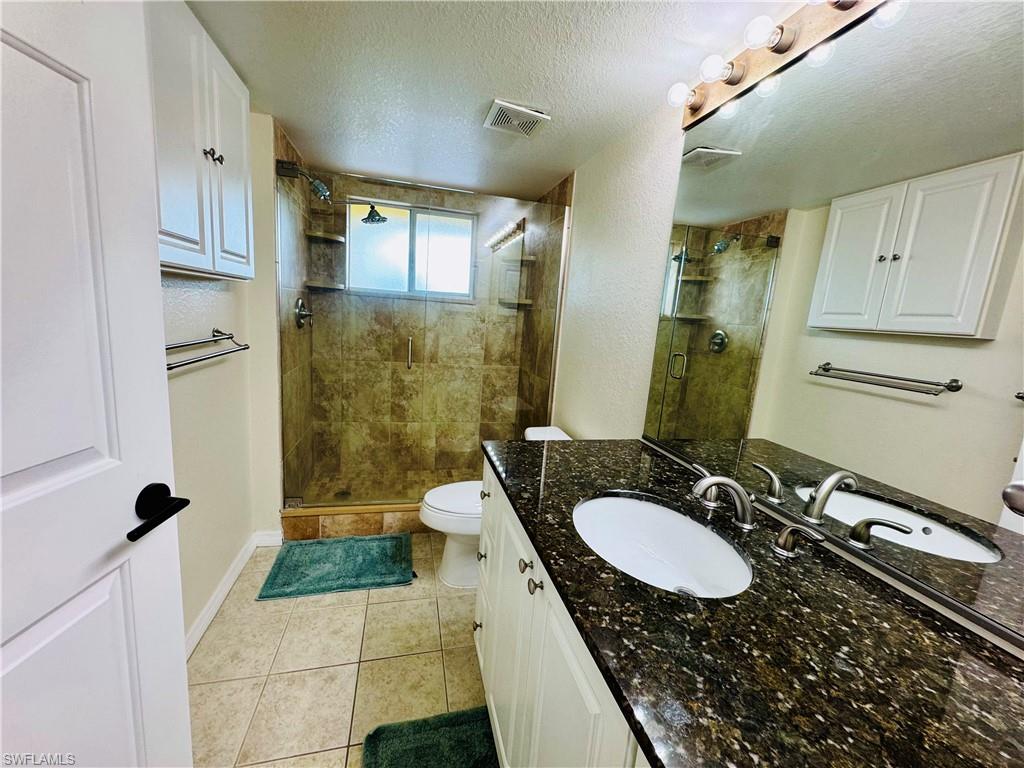 8244 Key Royal Circle, Unit 633 Naples, FL 34119 - Photo 8 of 28 a bathroom with a granite countertop sink a mirror and a shower