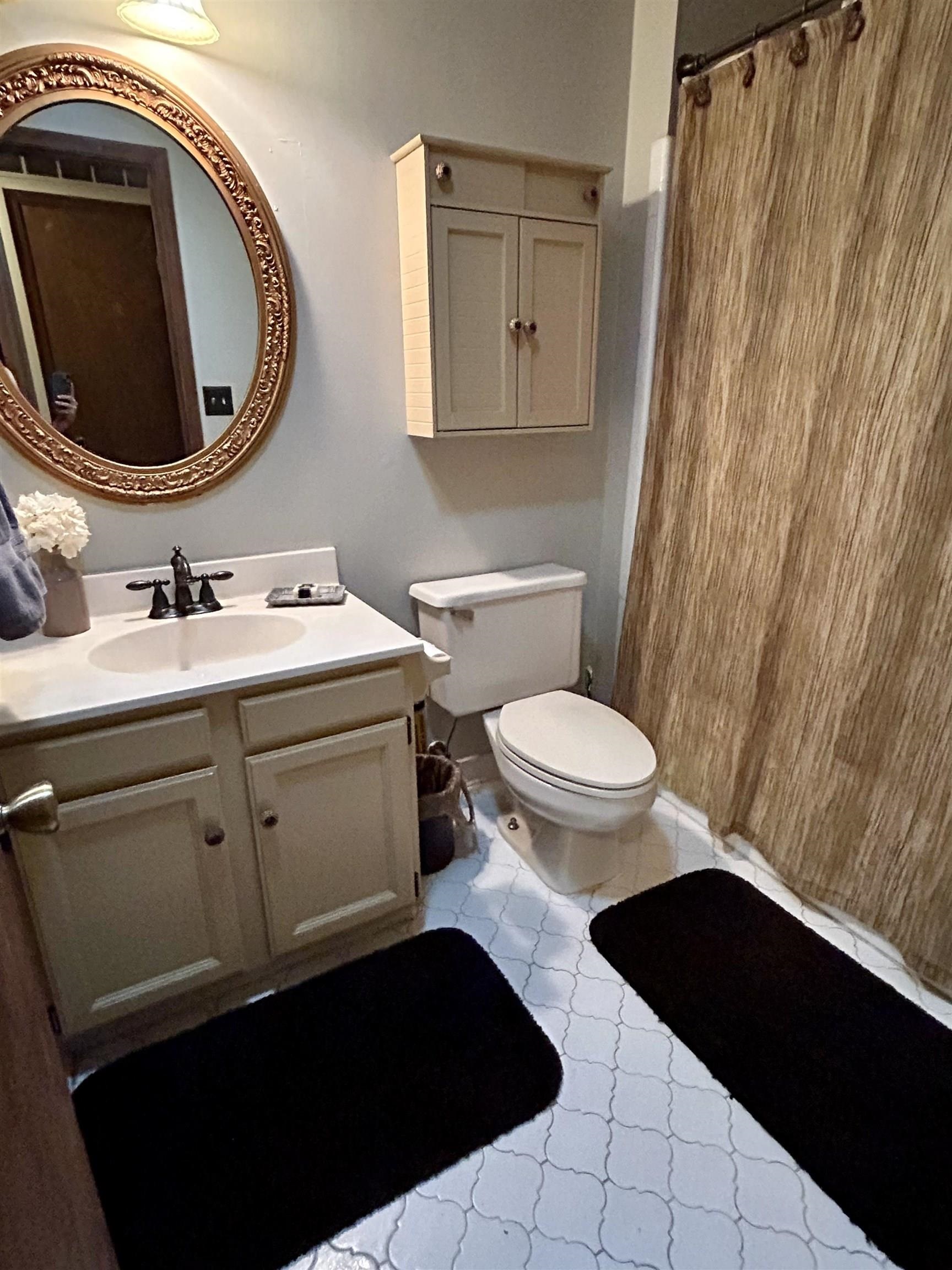Bathroom with vanity, light tile patterned floors, and a shower with shower curtain