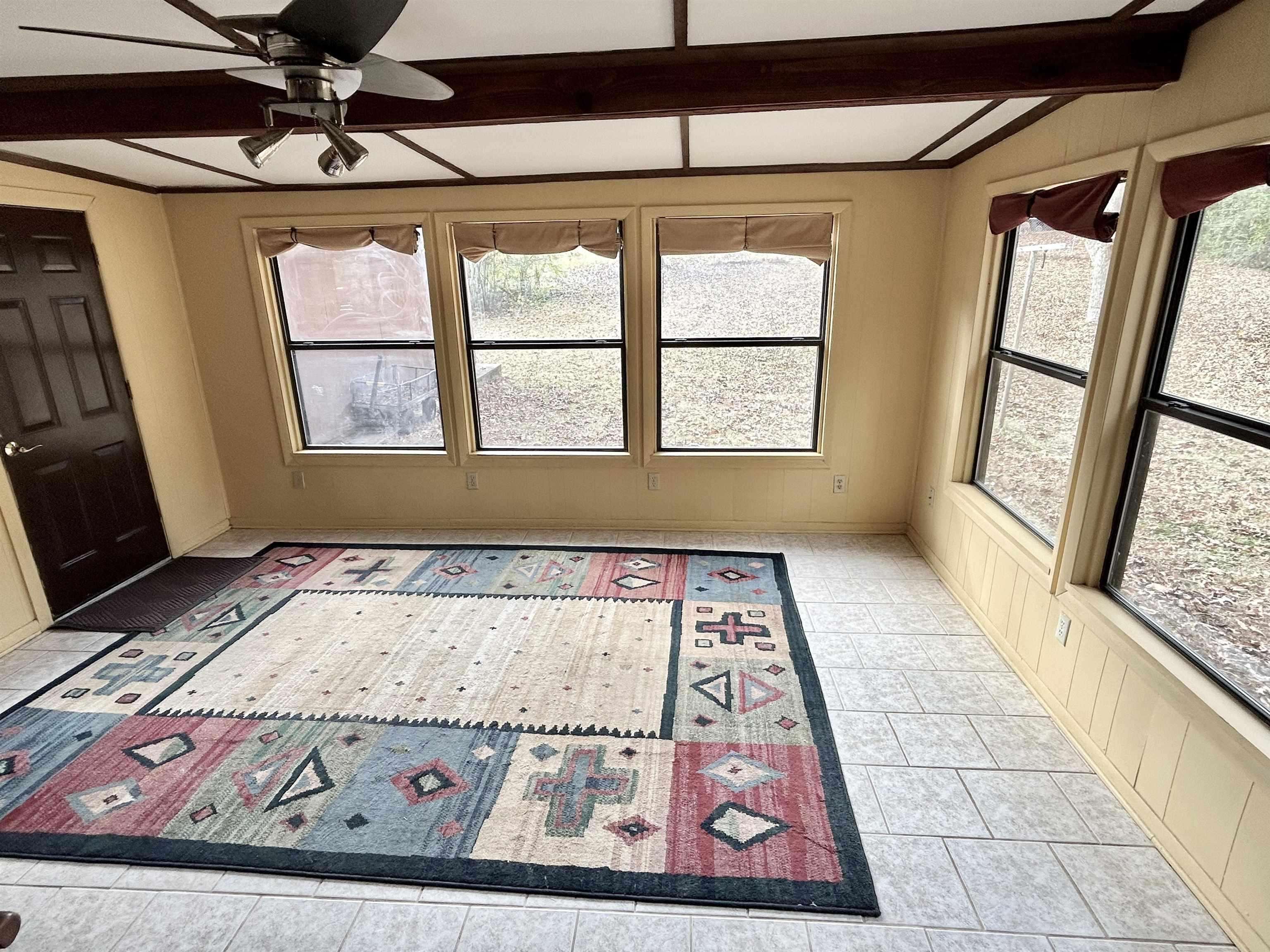 Entryway featuring a ceiling fan, beam ceiling, and light tile patterned flooring