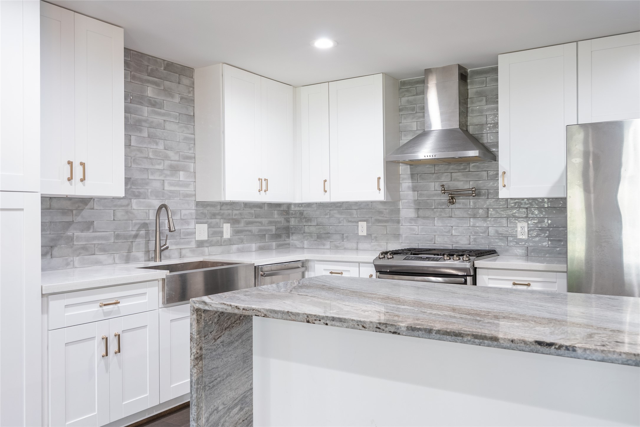 7307 Raton Street Houston, TX 77055 - Photo 13 of 23 Gray tile backsplash extends to the ceiling, offering a sophisticated touch to this modern kitchen!