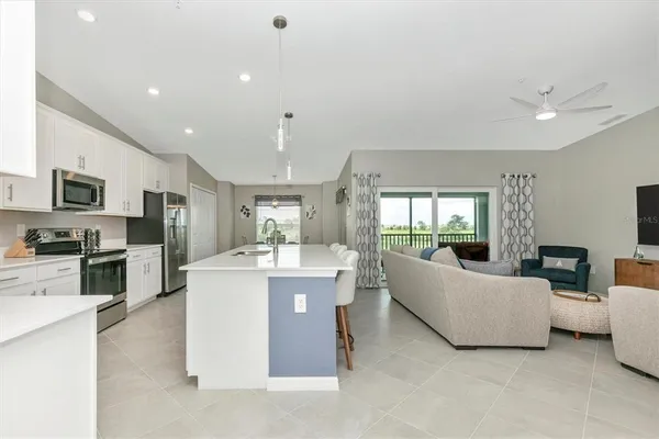 a kitchen with granite countertop a sink a stove a refrigerator and white cabinets