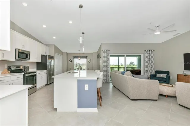 a kitchen with granite countertop a sink a stove a refrigerator and white cabinets