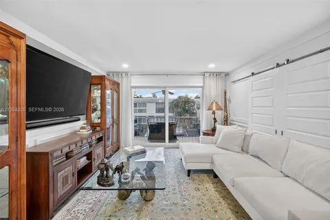 a bedroom with a bed a couch and a flat tv screen on the dresser