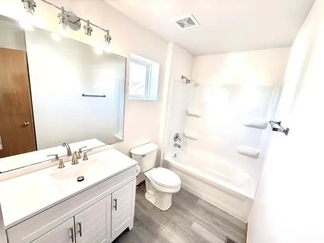 a bathroom with a sink a toilet a large mirror and shower