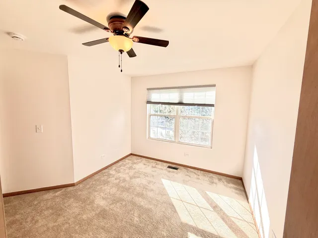 an empty room with a window and a ceiling fan