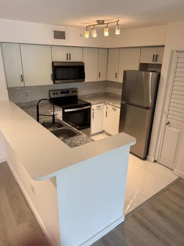 a kitchen with stainless steel appliances granite countertop a stove refrigerator sink and microwave