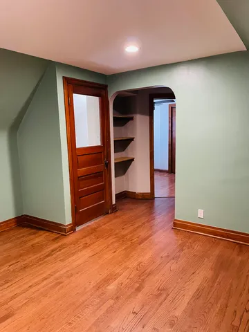 an empty room with wooden floor and entrance