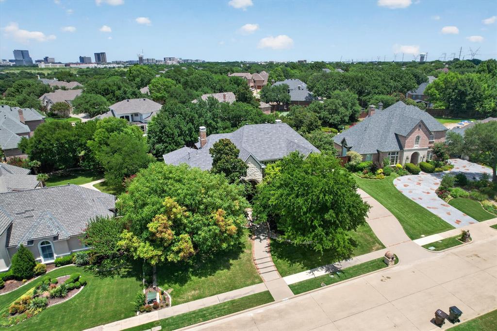 6416 Riverside Drive Plano, TX 75024 - Photo 31 of 35 Residential property featuring extensive green landscaping, a large driveway with decorative stone accents, and a brick and stone exterior facade