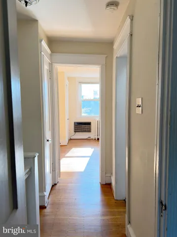a view of a hallway with wooden floor and a living room
