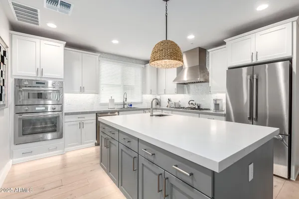 a kitchen with stainless steel appliances granite countertop a sink a stove a refrigerator and a center island