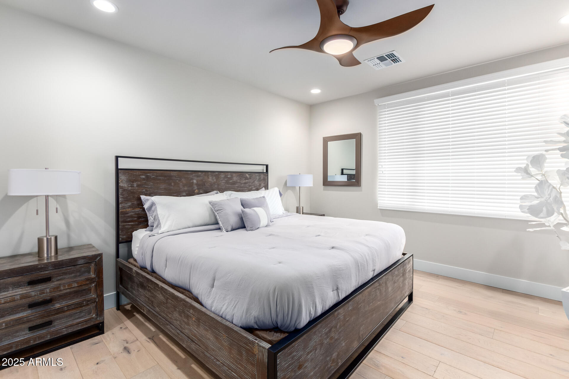 7550 East Osborn Road, Unit 1002 Scottsdale, AZ 85251 - Photo 4 of 23 a large bed sitting in a bedroom next to a window and a chandelier