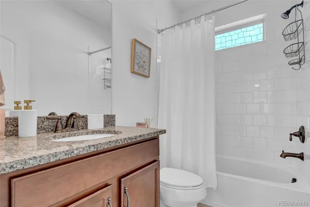 a bathroom with a granite countertop sink a toilet and shower