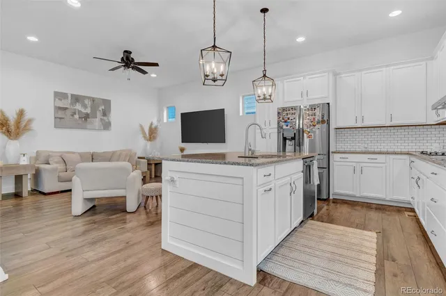 a large white kitchen with a refrigerator a stove a sink dishwasher and a fireplace with wooden floor