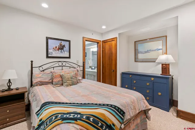 a bedroom with a bed and a lamp on dresser