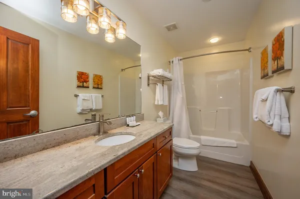 a bathroom with a granite countertop sink a toilet a shower and a mirror