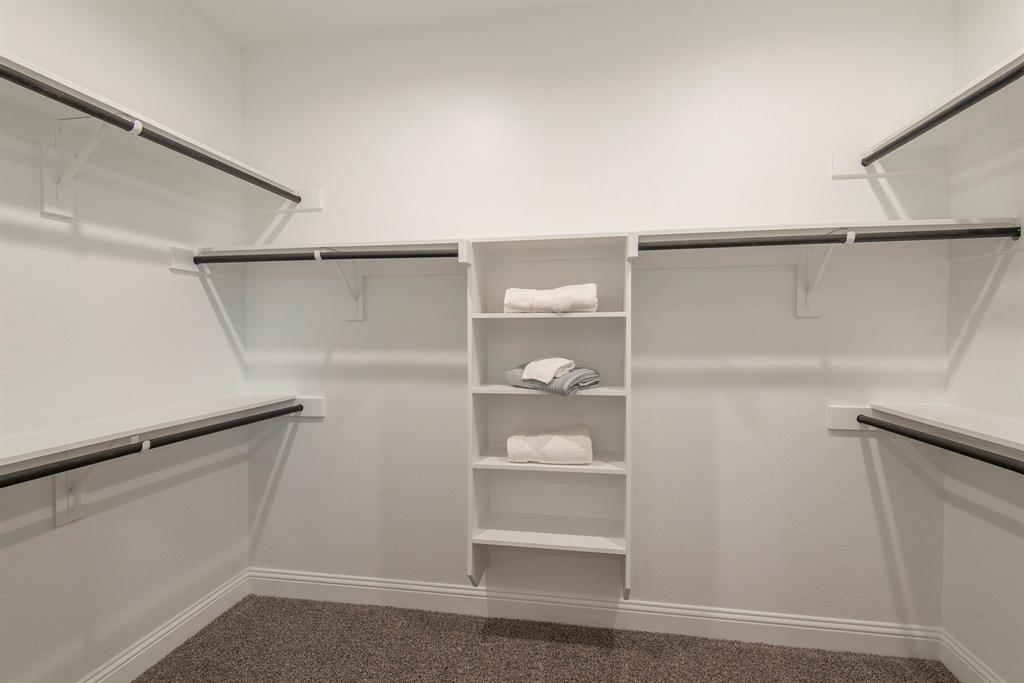 2301 Ruff Road Denton, TX 76205 - Photo 15 of 23 Spacious walk-in closet in primary bathroom featuring built-in shelving, multiple hanging rods, and textured carpeting