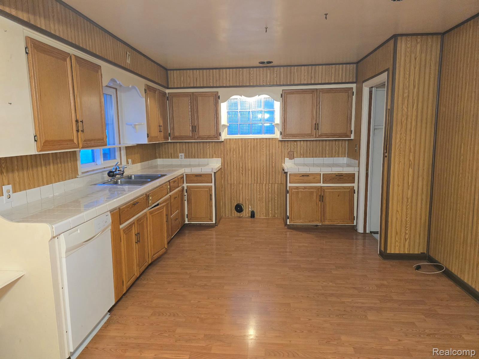 803 Commonwealth Avenue Flint, MI 48503 - Photo 7 of 15 Kitchen featuring tile counters, white dishwasher, light wood-style flooring, and wood finish cabinets