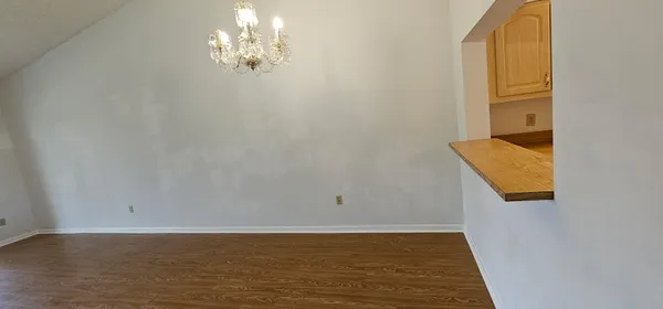 a view of empty room with chandelier fan and wooden floor
