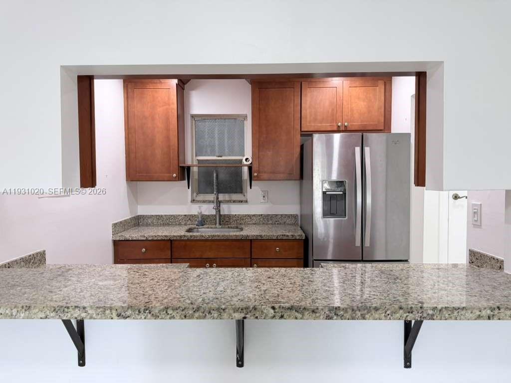 160 Southwest 30th Avenue, Unit 104A Miami, FL 33135 - Photo 11 of 32 a kitchen with kitchen island a counter top space cabinets a sink and a window