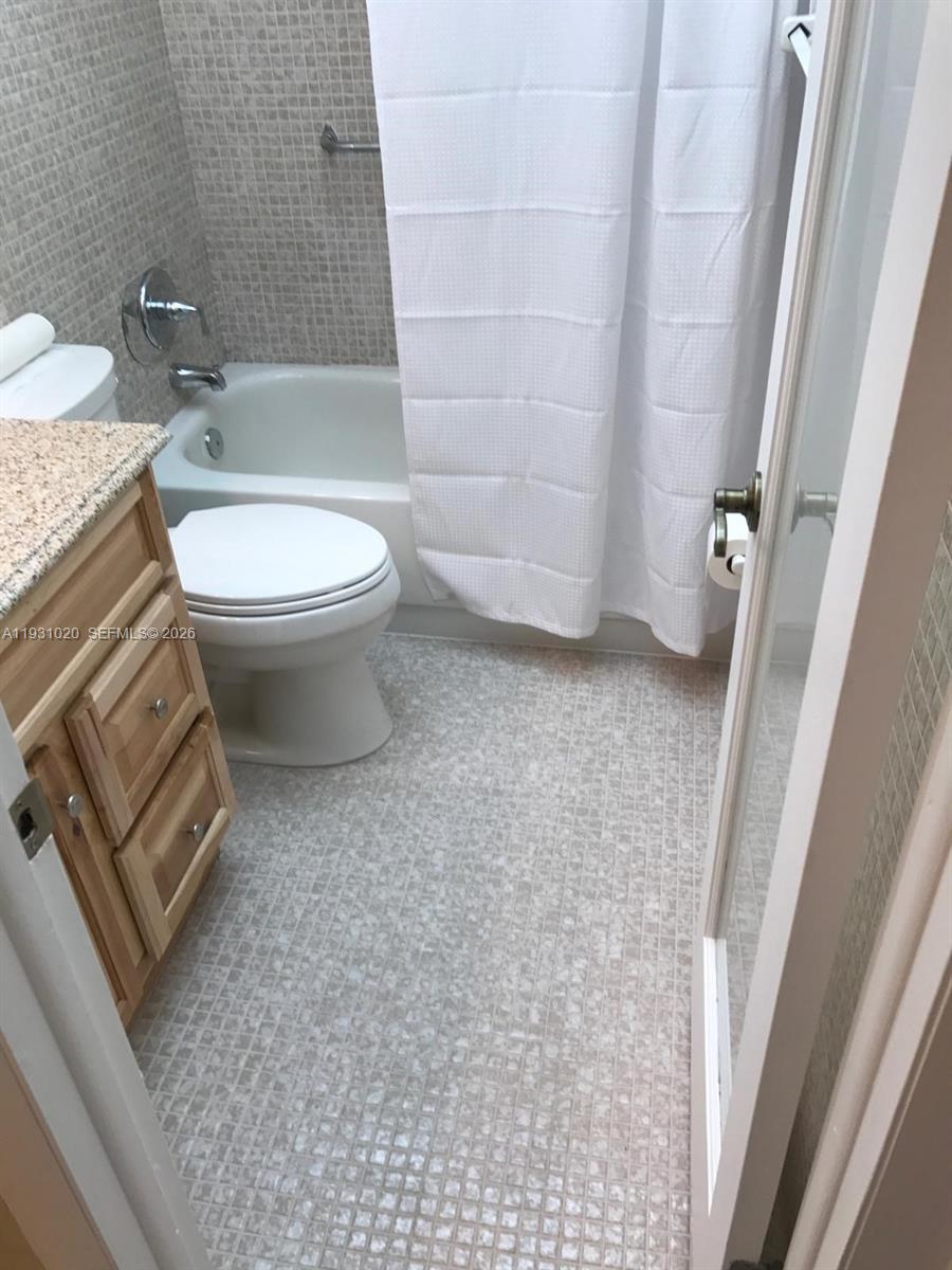 160 Southwest 30th Avenue, Unit 104A Miami, FL 33135 - Photo 13 of 24 a bathroom with a granite countertop toilet a sink and a mirror