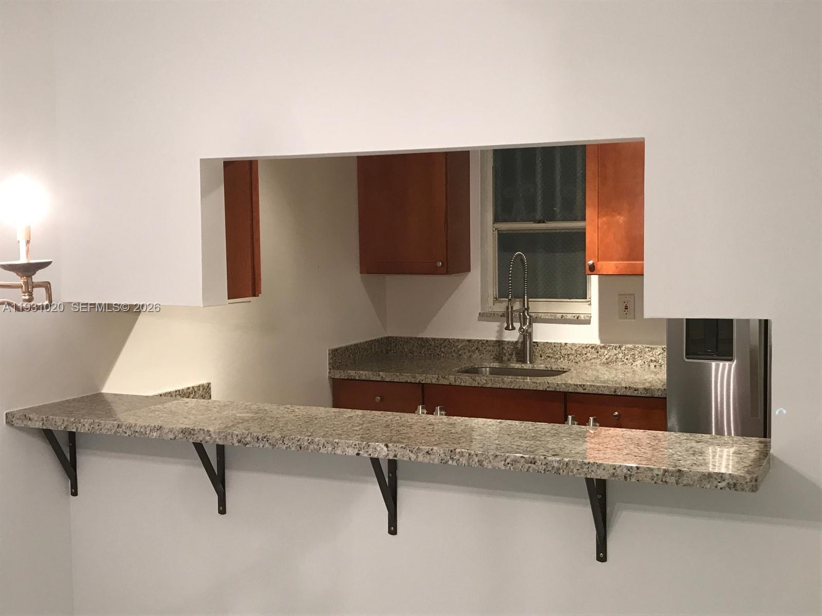 160 Southwest 30th Avenue, Unit 104A Miami, FL 33135 - Photo 22 of 24 a kitchen with a sink and wooden cabinets