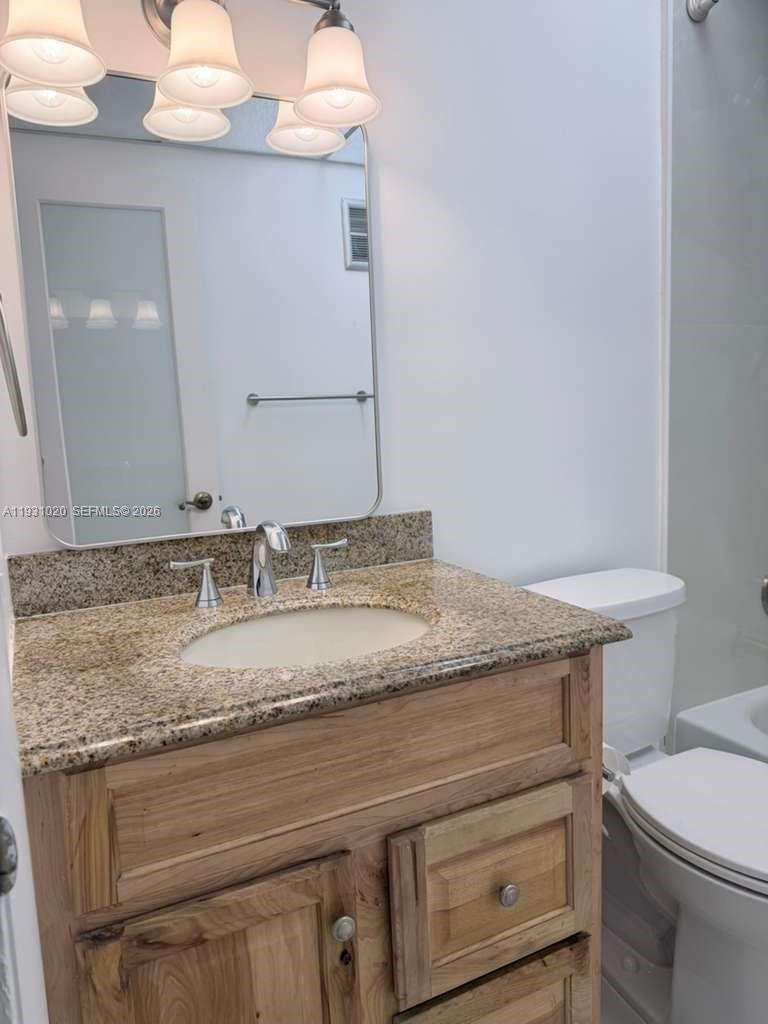 160 Southwest 30th Avenue, Unit 104A Miami, FL 33135 - Photo 4 of 32 a bathroom with a granite countertop sink and a toilet