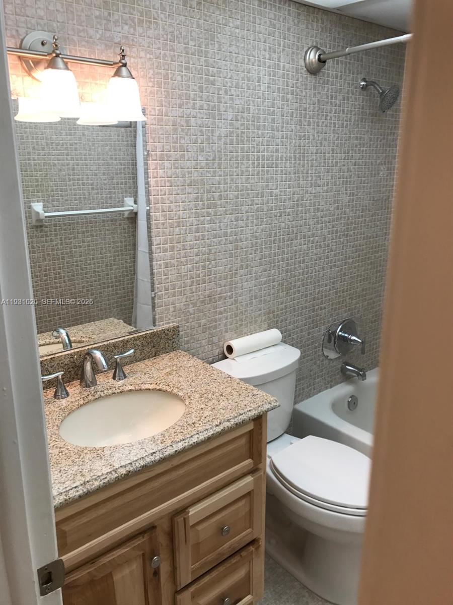 160 Southwest 30th Avenue, Unit 104A Miami, FL 33135 - Photo 4 of 24 a bathroom with a granite countertop toilet sink and mirror