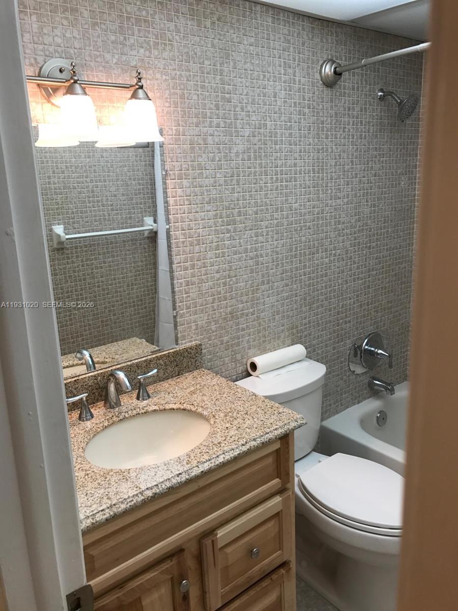 160 Southwest 30th Avenue, Unit 104A Miami, FL 33135 - Photo 9 of 24 a bathroom with a granite countertop sink and a mirror