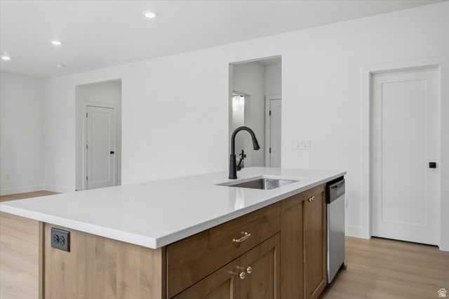 844 North 400 West Logan, UT 84321 - Photo 12 of 43 Kitchen island featuring a white countertop, undermount sink with a matte black gooseneck faucet, light wood-finish cabinetry, and an integrated stainless steel dishwasher