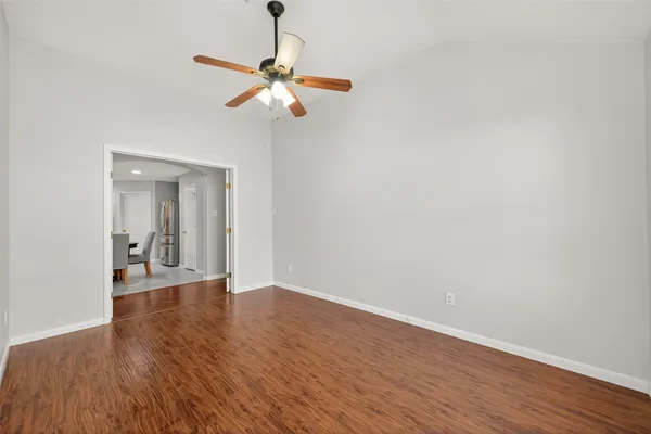 an empty room with wooden floor fan and windows
