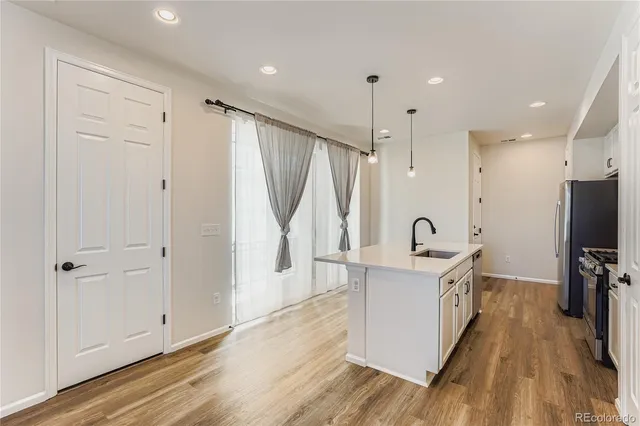 a large white kitchen with a sink a window and stainless steel appliances