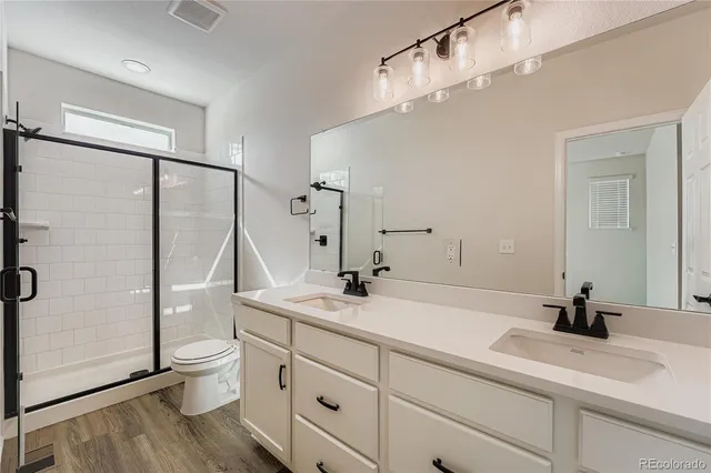 a bathroom with a double vanity sink toilet and shower