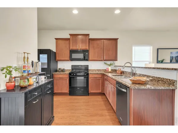 a kitchen with stainless steel appliances granite countertop a stove a sink dishwasher and a refrigerator with wooden cabinets
