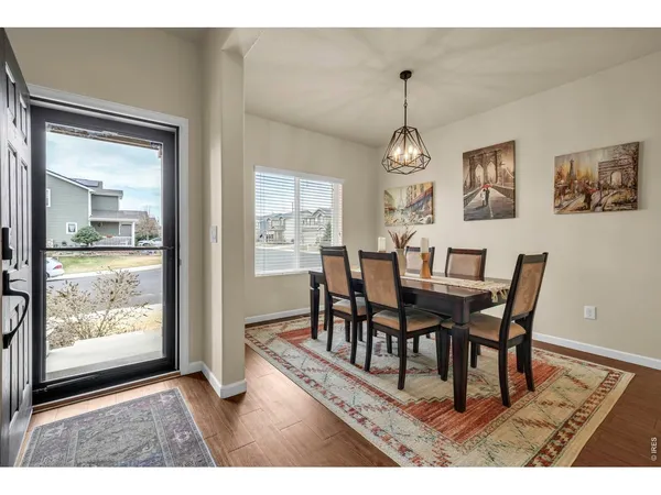 a view of a dining room and livingroom with furniture wooden floor a rug a painting and a chandelier
