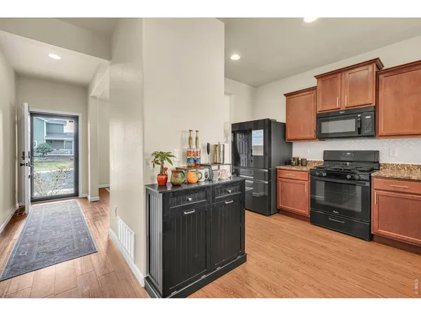 a kitchen with stainless steel appliances kitchen island granite countertop a refrigerator stove and sink