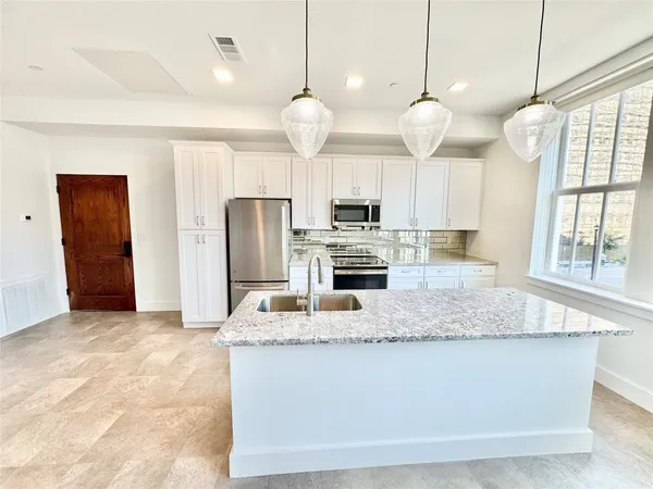 a large kitchen with kitchen island granite countertop a stove a refrigerator a oven and a sink