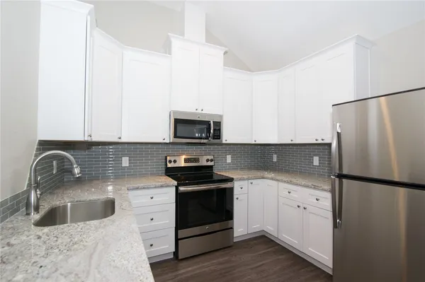 a kitchen with granite countertop a sink a stove and refrigerator
