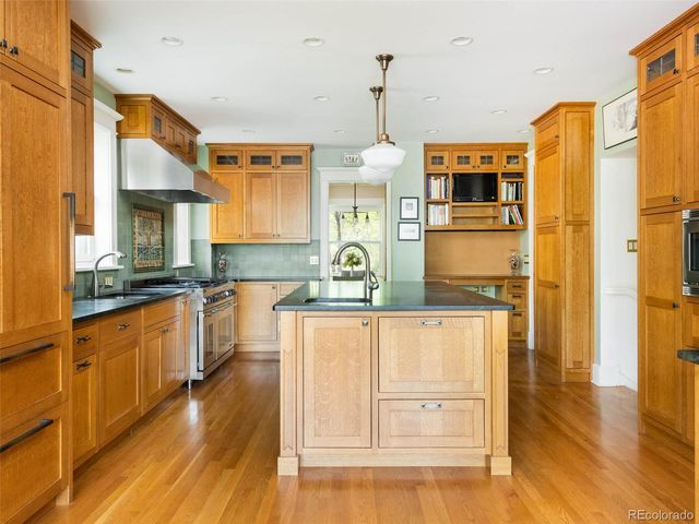 a kitchen with stainless steel appliances granite countertop a sink a stove and wooden floors