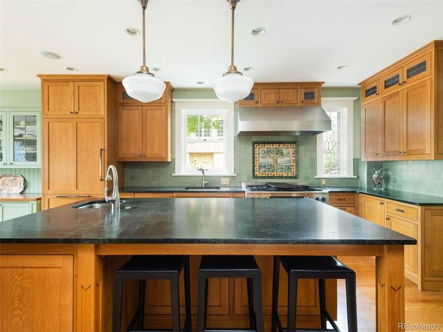 a kitchen with granite countertop a stove a sink dishwasher and cabinets with wooden floor