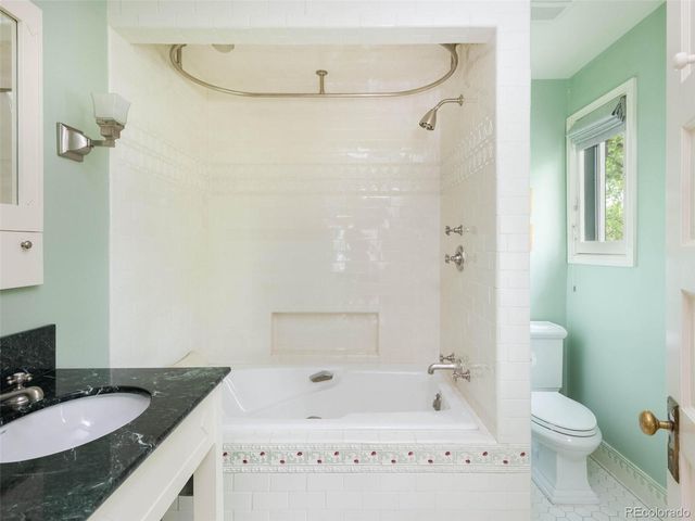 a bathroom with a granite countertop sink a toilet and shower