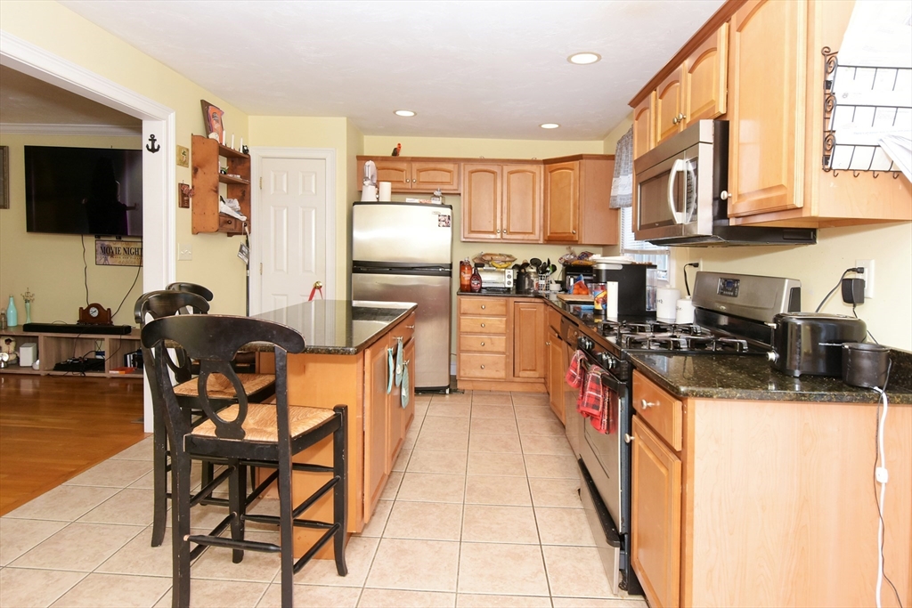 966 Washington Street, Unit 2 Weymouth, MA 02189 - Photo 7 of 25 a kitchen with stainless steel appliances granite countertop a stove top oven a sink a dining table and chairs