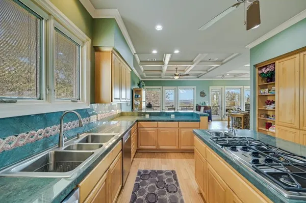 a kitchen with stainless steel appliances kitchen island granite countertop a table chairs sink and cabinets