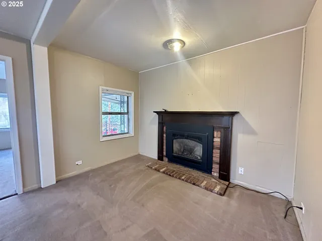 a view of an empty room with window and fire place