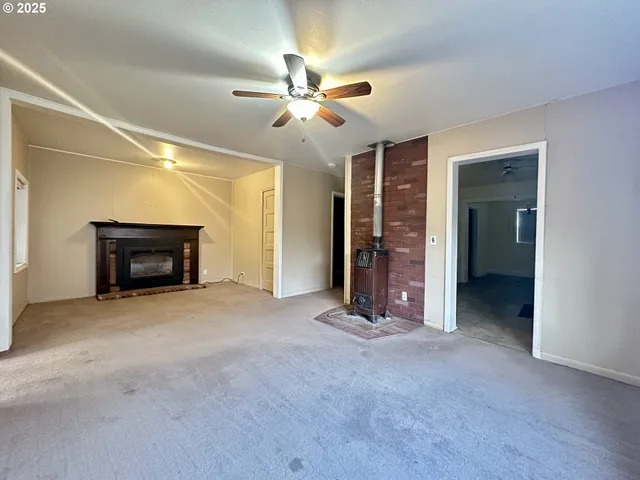 a view of an empty room with chandelier fan and fire place