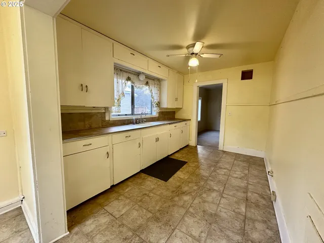 a large white kitchen with a large window appliances and cabinets